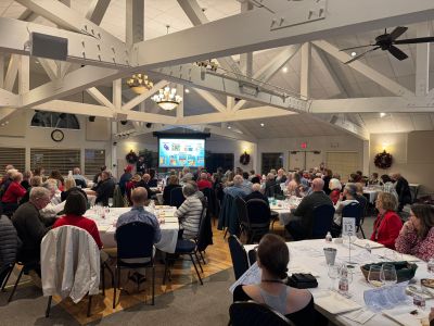 Large gathering in banquet hall with speaker and presentation.
