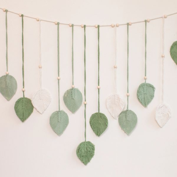 Decorative garland with hanging green and white yarn leaves and wooden beads.