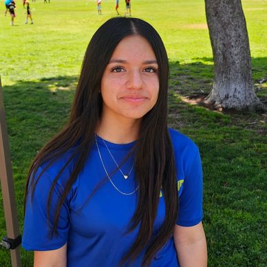 Young woman in a blue shirt outdoors on a sunny day.
