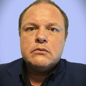 Close-up of a serious man with a blue background.
