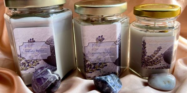 Three lavender-scented anxiety relief candles with crystals on satin fabric.