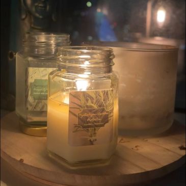 Lit candle on a wooden tray with a Buddha statue in the background at night.
