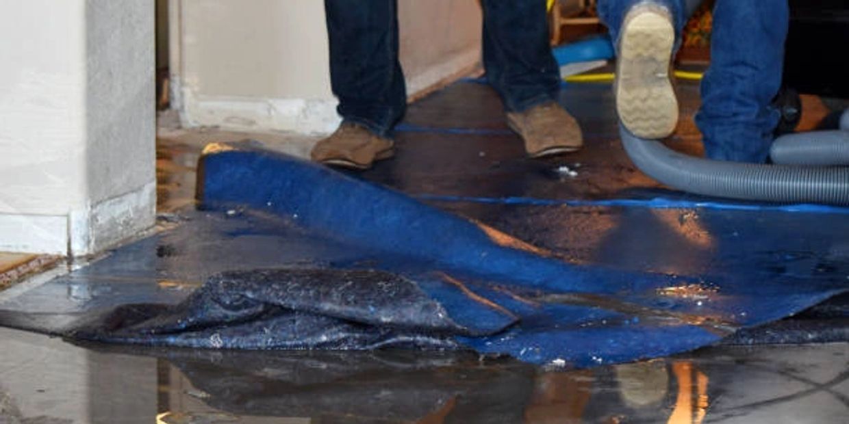 Water flooding inside a house with people standing on wet floor.