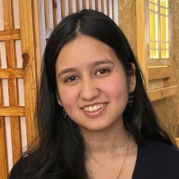Young woman smiling indoors with wooden background.