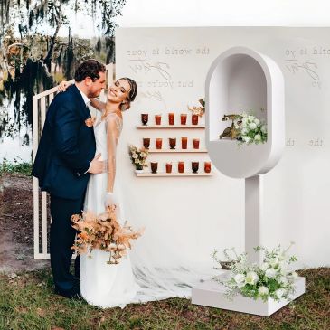 Happy couple posing by a modern wedding decor setup outdoors.