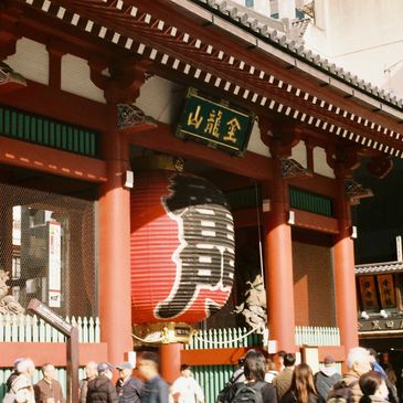 Crowded entrance of a traditional Japanese temple with a large red lantern.