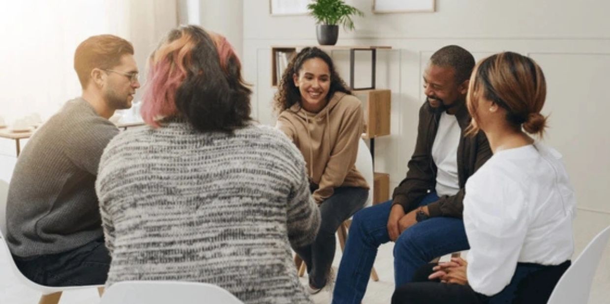 Diverse group engaged in a warm, friendly discussion in a cozy room.
