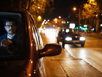 Man driving a car at night on a city street.