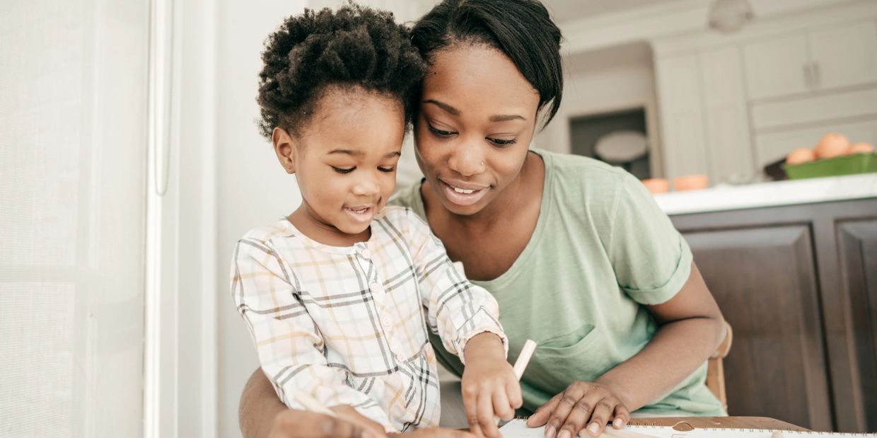A mother and daughter happily drawing together at home.