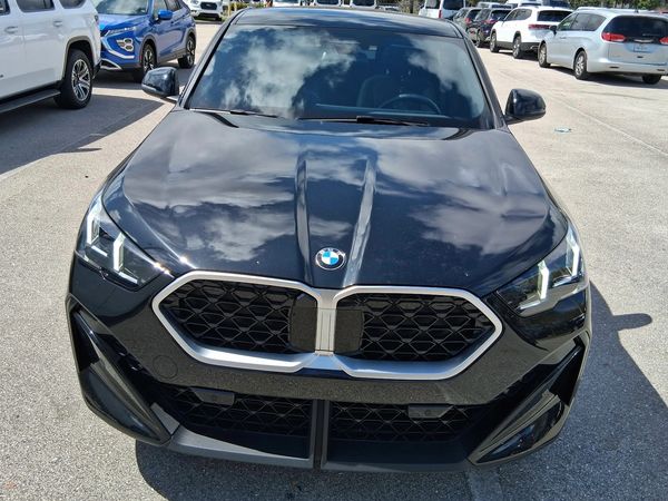 Front view of a black BMW parked in a lot.
