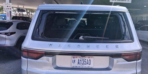 Rear view of a silver Wagoneer SUV with a cracked rear window and a license plate.