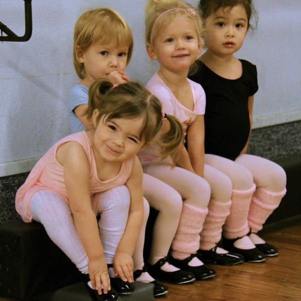 Four young girls in ballet attire sitting together.