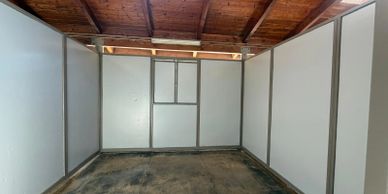 Empty room with white panel walls and wooden ceiling.