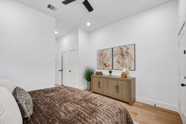 Minimalist bedroom with brown bedding and wooden sideboard.