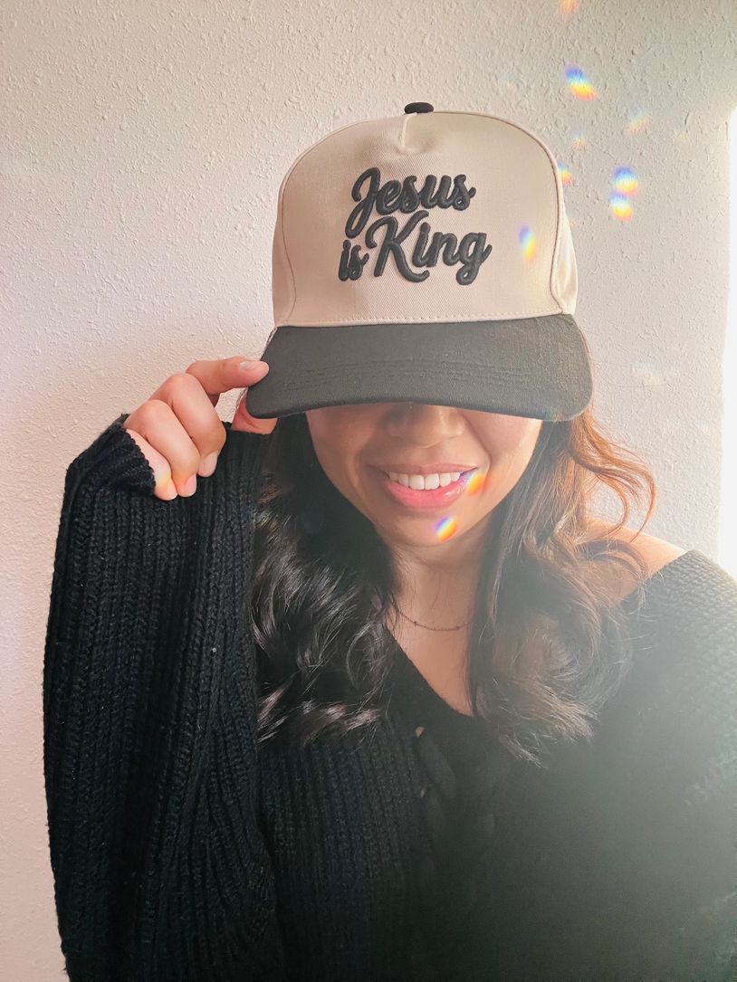 Woman smiling with a cap that says 'Jesus is King'.