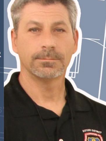 Man in a black shirt with an official emblem.