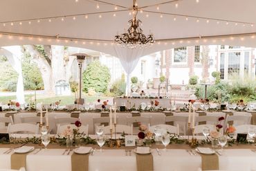 long tables with white table cloths, linen table runners and floral bud vases with greenery garland
