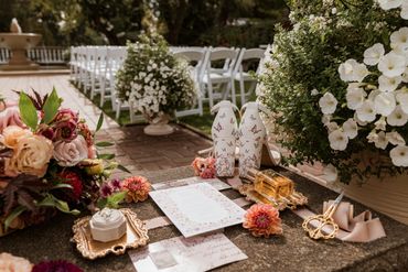 wedding invitation on stone bench surrounded by rings, flowers, and bride's shoes.