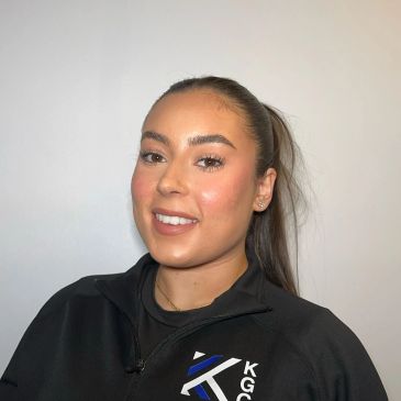 Smiling young woman with ponytail in black jacket.