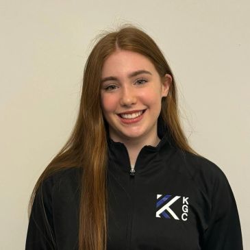 Smiling young woman with long hair in a black jacket.