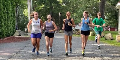 Five people running outdoors on a gravel path.