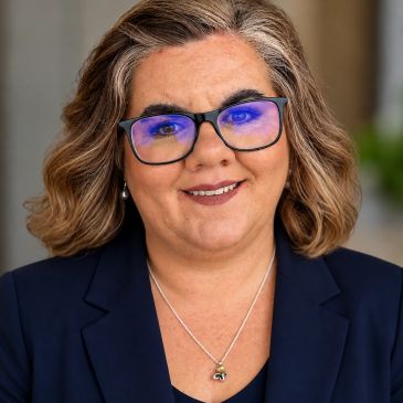 Professional woman wearing glasses and a navy blazer.