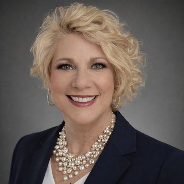 Professional woman with blonde curly hair and pearl necklace.