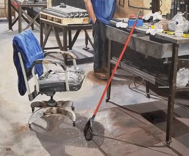 A Chair, a broom, and a desk in a manufacturing machine shop.