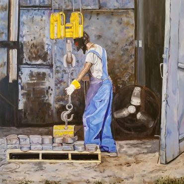 A man moving metal parts with a crane in a warehouse.