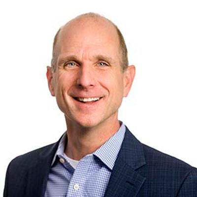 Smiling bald man in business attire against a white background.