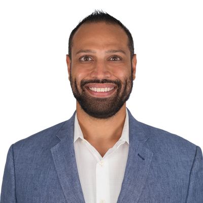 Smiling man in blue blazer and white shirt against white background.
