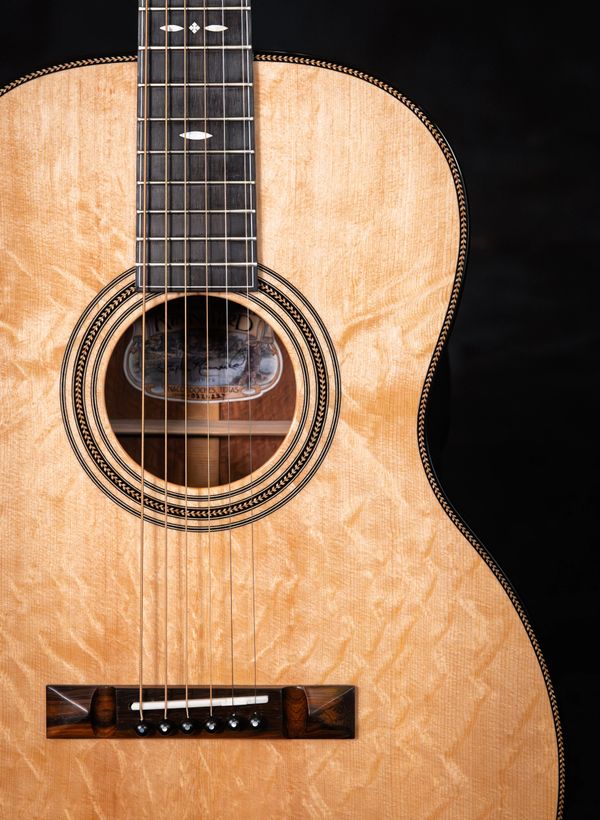 Close-up of an acoustic guitar's body and strings with a wooden finish.