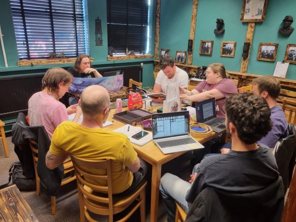 Group of people engaged in a tabletop role-playing game session in a cozy room.