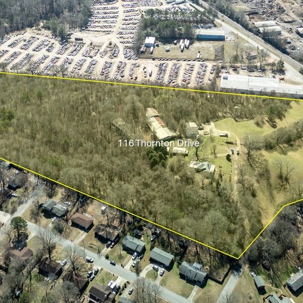 Aerial view of 116 Thornton Drive property outlined in yellow with wooded and cleared areas.