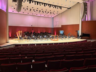 Empty concert hall with stage set for orchestra performance.