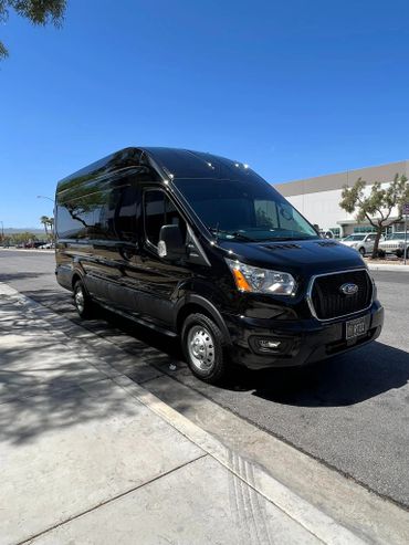 Black Ford Transit van parked on a sunny street.