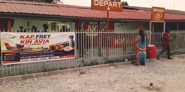 Bus station with sign 'DEPART' and advertisement banner in front.