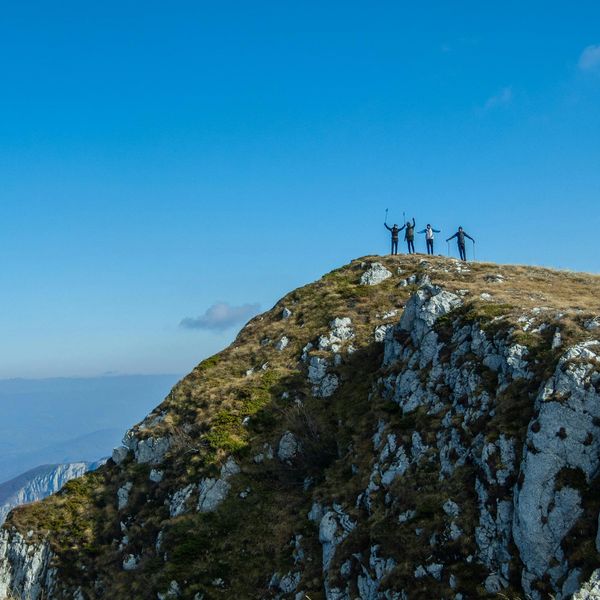 Hikers at the summit overlooking the ocean under blue sky
