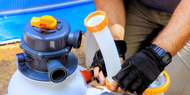 Person assembling a pool pump with gloves and tools.