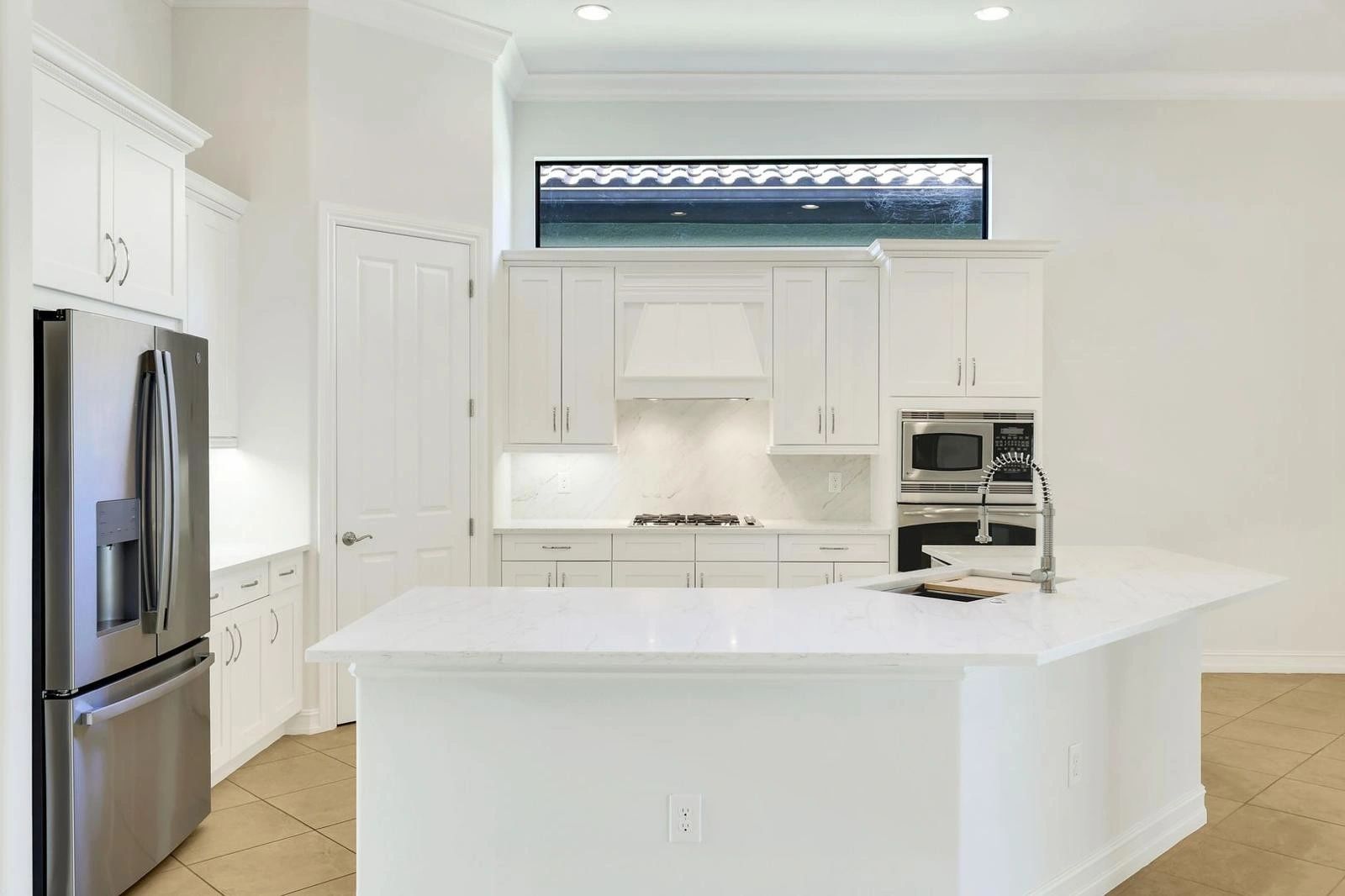 Modern white kitchen with stainless steel appliances and a large island.