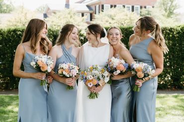 Bride and Bridesmaid smiling and hold flower bouquets
