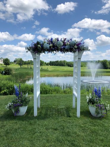 Purple, blue and lavender flowers on a white arbor. 