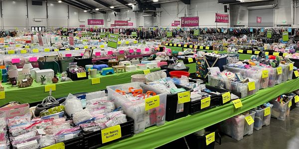 Indoor sale event with labeled bins and clothes racks.