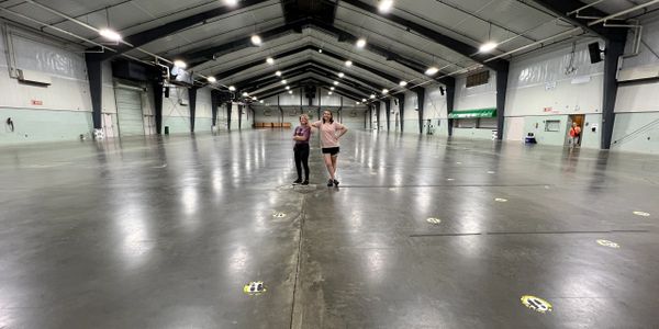 Two girls standing in a vast empty hall.