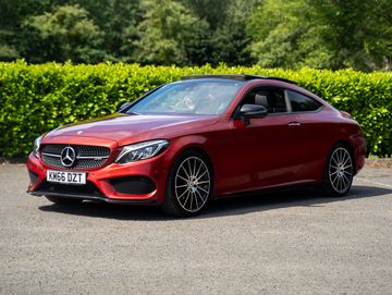 Red Mercedes-Benz coupe parked outdoors on a sunny day.