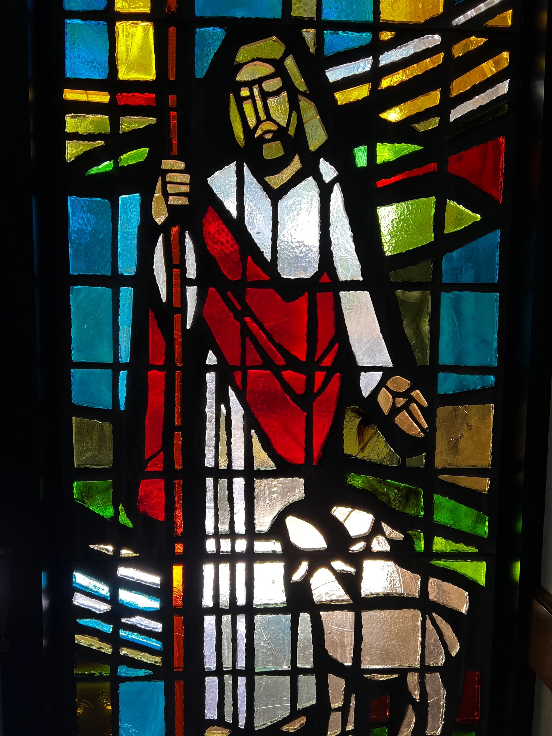 Stained glass of a robed figure holding a staff.