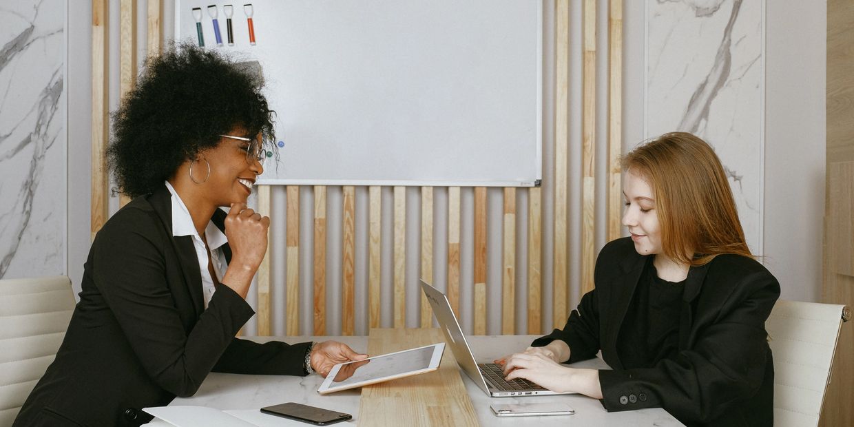 Two women talking holding electronic devices