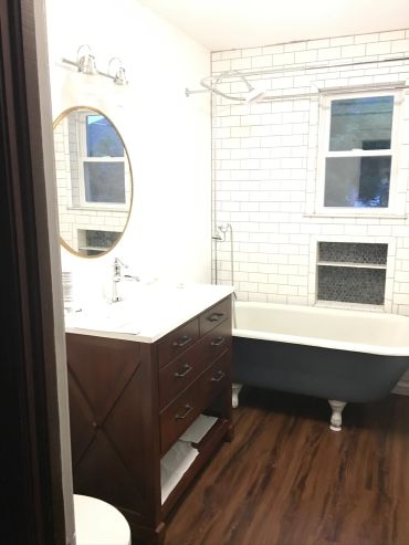 Bright bathroom with clawfoot tub and wooden vanity.