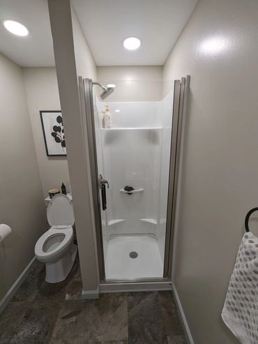 Small bathroom with glass shower and toilet.