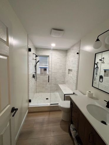 Modern bathroom with glass shower enclosure and wooden vanity.